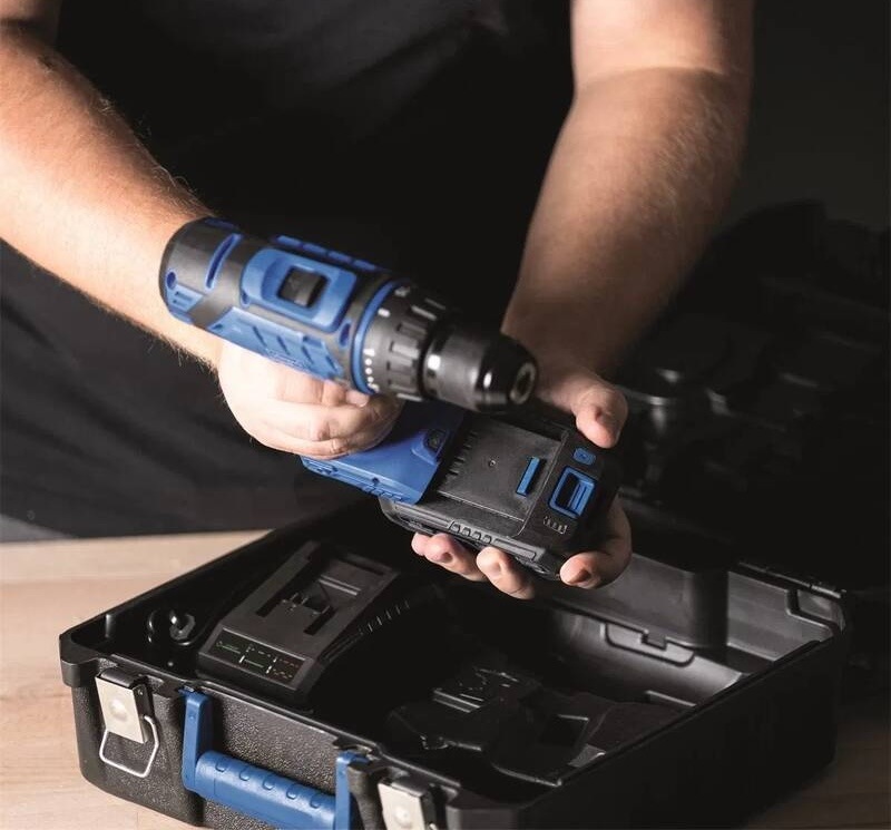 Vŕtací skrutkovač Scheppach C-DTB74/1-X - 20 V IXES (s baterií) Muž v dielni nasadzuje 20V lítium-iónovú batériu na aku vŕtačku Scheppach nad otvoreným kufrom