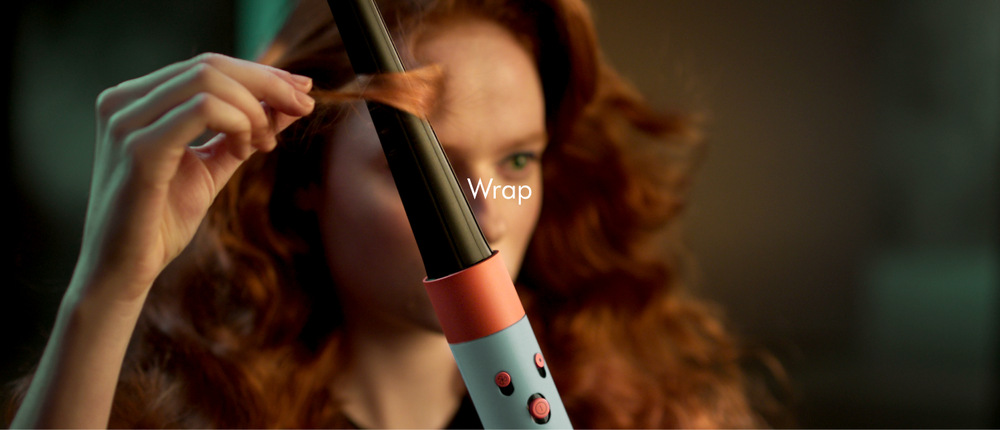 Multistyler Dyson Airwrap i.d. HS08 T3/T4 rose gold/ceramic pink Lifestyle stylingový moment, osoba natáča prameň vlasov s kulmovým nástavcom, práca s horúcim vzduchom, dynamický pohyb prameňa, precízny úchop počas tvorby lokne