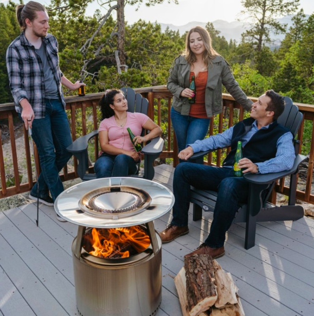 Deflektor tepla Solo Stove Bonfire Skupina ľudí sedí okolo ohniska Solo Stove Bonfire s deflektorom tepla pri večernom posedení na terase