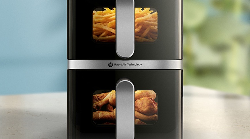 Fritéza teplovzdušná Philips Airfryer Dual Basket 4000 series 10 l, NA461/00 čierna Detail teplovzdušnej fritézy Philips NA461/00 s dvoma košmi, v ktorých sú cez priehľadné okienka vidieť hranolky v hornej časti a kuracie paličky v spodnej časti, uprostred je označenie technológie RapidAir.