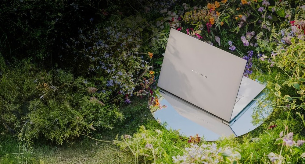 Asus Zenbook S16 položený v záhrade medzi kvetinami zdôrazňuje spojenie dizajnu s prírodou