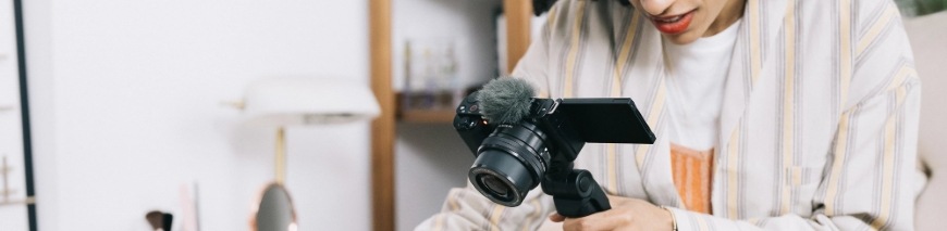 Digitálny fotoaparát Sony ZV-E10 + 16-50 mm f/3.5-5.6 II čierny Žena zhotovujúca video pomocou vlogovacej kamery Sony ZV-E10