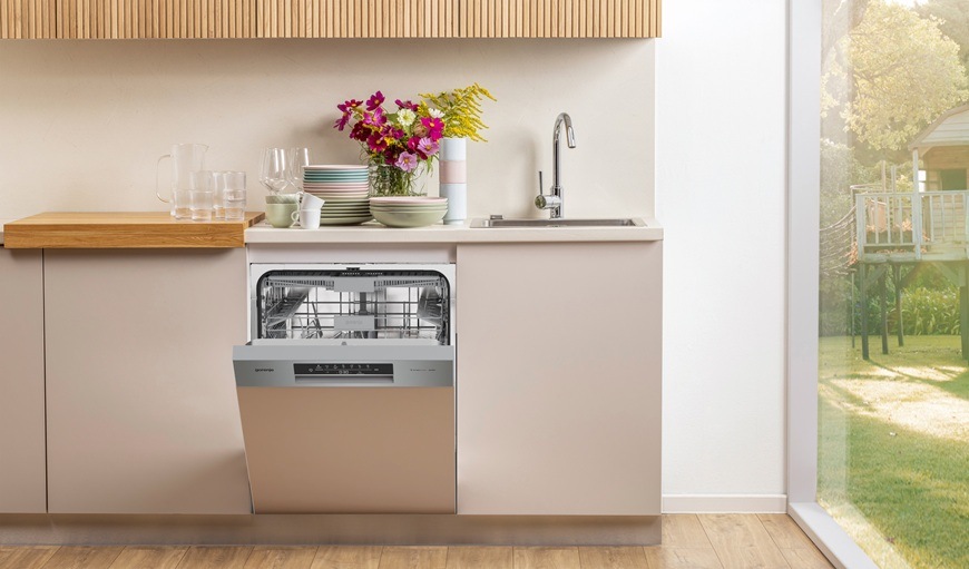 Umývačka riadu Gorenje G400 GI643C90X Vstavaná umývačka Gorenje GI643C90X je zabudovaná v kuchynskej linke. Jej dvierka sú pootvorené a na linke je váza s kvetinami.