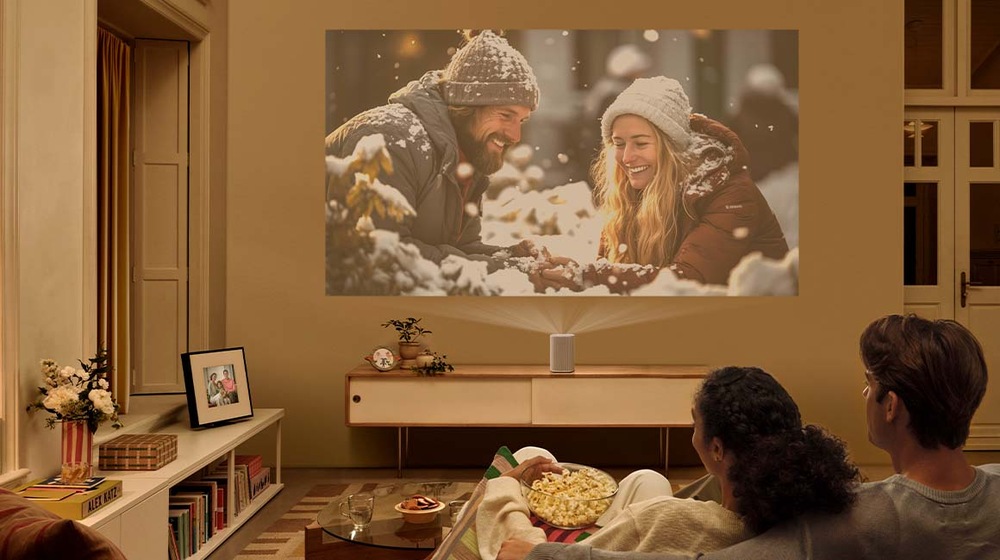 Laser TV Samsung SP-LPF5DSA Dvaja ľudia sedia v obývacej izbe a sledujú film premietaný projektorom The Premiere 5 na stenu
