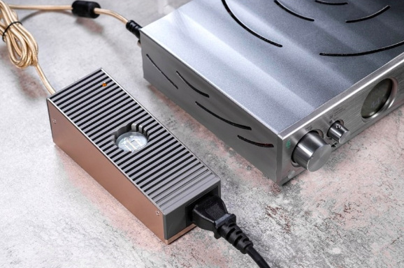 Sieťový adaptér SilentPower iPower Elite 15V sivý Napájací adaptér iFi SilentPower iPower Elite 15V pri zapojení k audio technike doma na stole