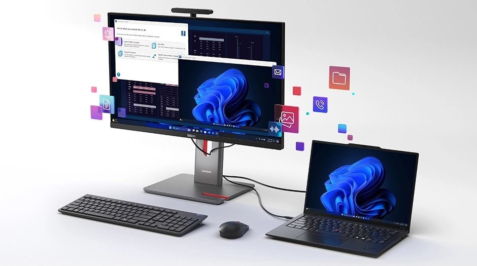 PC all in-one Lenovo ThinkCentre M90a Pro Gen 6 čierny/sivý All In One počítač je pripojený k notebooku s klávesnicou a myšou pred nimi. Po obrazovke sa vznášajú ikony rôznych aplikácií, ktoré naznačujú multitasking alebo používanie viacerých aplikácií.