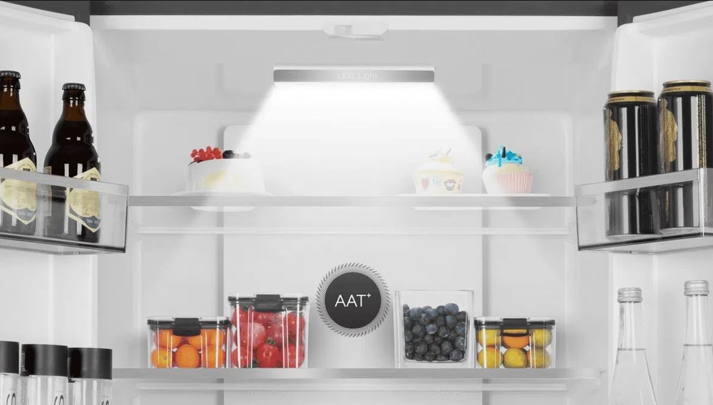 Je vidieť osvetlenie chladničky TCL RP403FXE0EU, na policiach sa nachádzajú potraviny v krabičkách, vo dverách sú fľaše