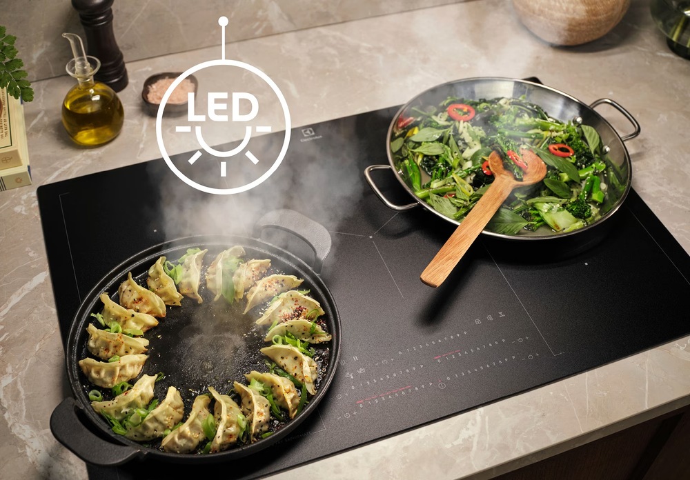 Odsávač pár Electrolux série 500 LFC516X nerez Varná doska Electrolux s panvicou raviol a zeleniny. Nad doskou symbol pre LED osvetlenie.