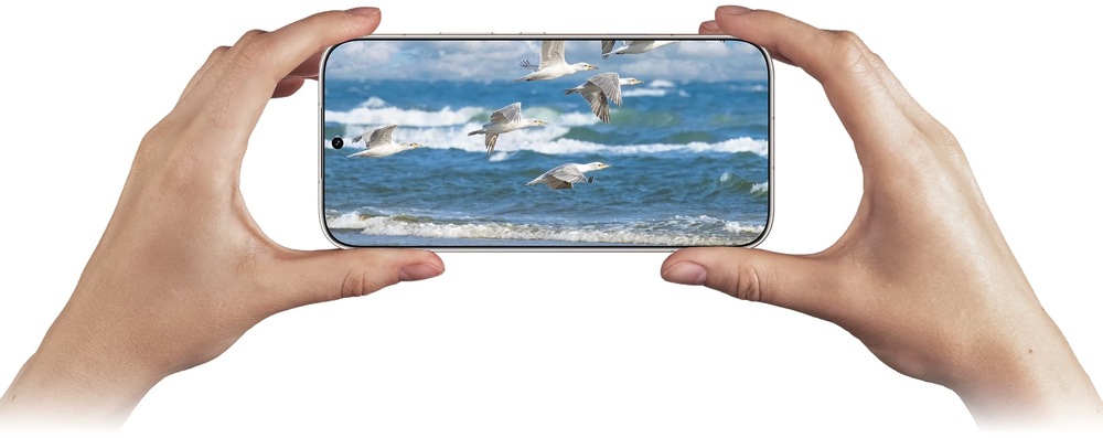 Ruky držiace HONOR 600 pri robení záberu s čajkami lietajúcimi nad rozbúreným morom