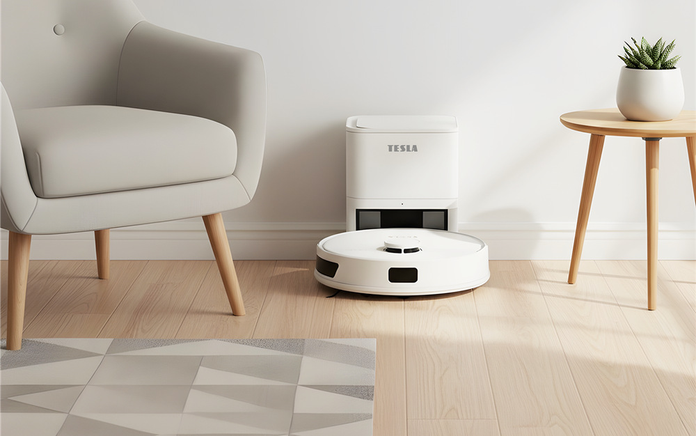 Robotický vysávač Tesla RoboStar iQ660 Plus biely Robotický vysávač Tesla RoboStar iQ660 Plus stojí pred stanicou v obývacej izbe, vľavo je kreslo, vpravo stojí stolík s rastlinou v kvetináči