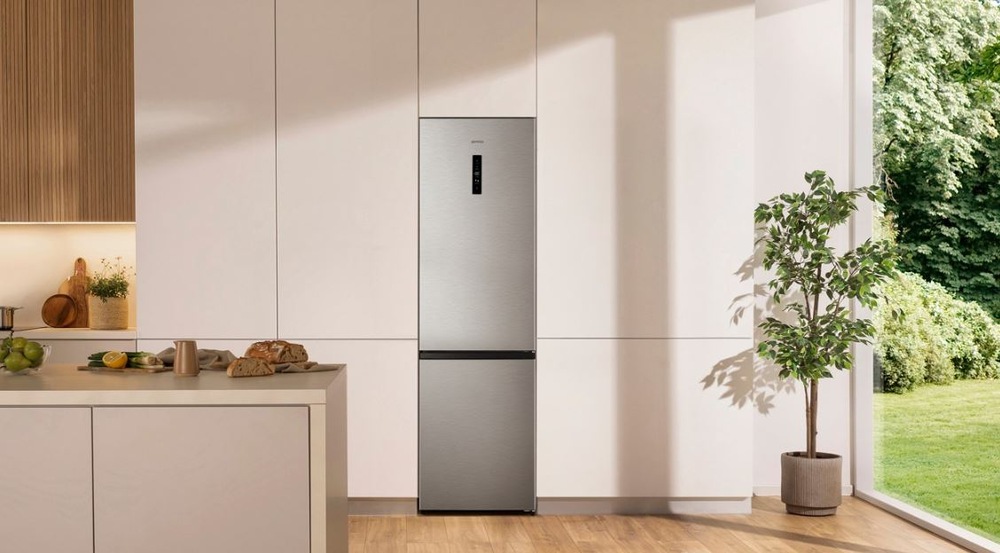 Chladnička s mrazničkou Gorenje G600 NRK620EAXL4 nerez zatvorená nerezova chladnicka Gorenje NRK620EAXL4 stojí vo svetle kuchyni, z boku svietia slnečné lúče zo záhrady cez presklenú stenu. Medzi chladničkou a stenou je rastlina v kvetináči