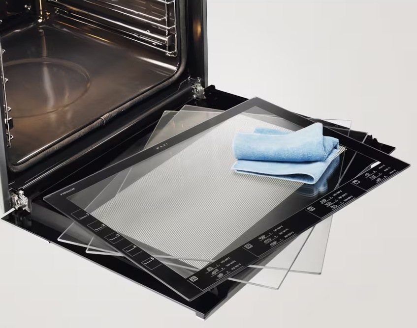 Otvorené dvierka rúry Electrolux. Na dvierkach sú položené sklenené panely a handričku.