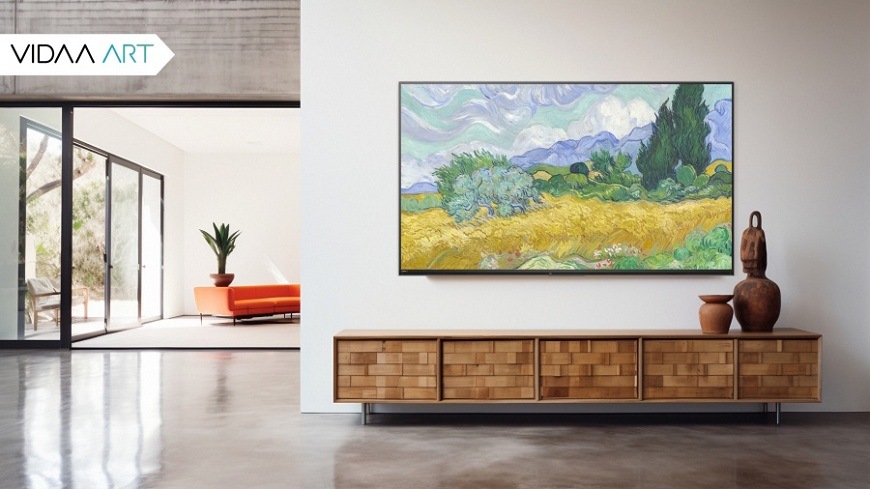 Televízia JVC visiaci na stene priestranného industriálneho domu, premietajúci obraz krajiny Vincenta van Gogha – Pšeničné pole s ciprišmi pomocou funkcie VIDAA ART