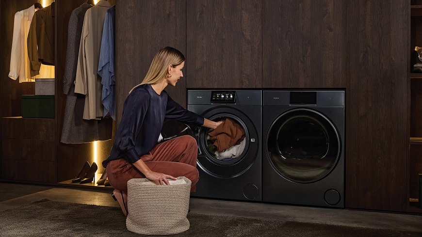 žena v práčovni plní práčku Haier HW100BD14L8GNU1S bielizňou