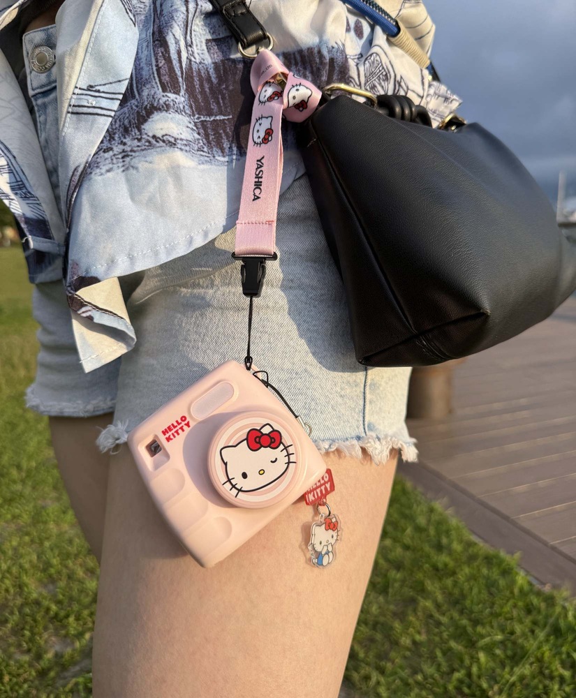 Digitálny fotoaparát Yashica x Hello Kitty Mini Digital Camera ružový Kompaktný fotoaparát Yashica x Hello Kitty zavesený na popruhu pripnutom k kabelke
