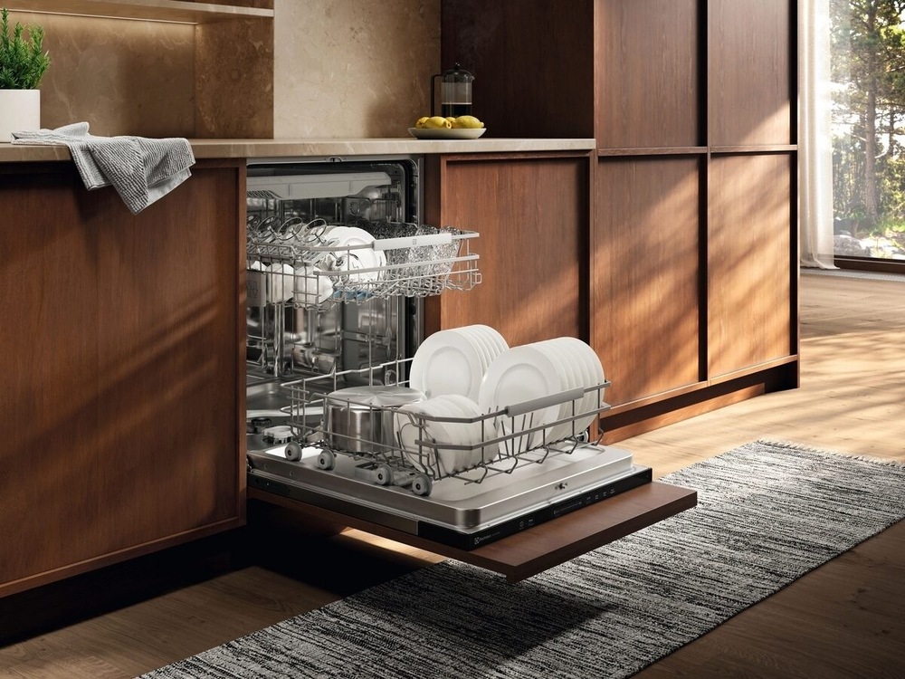 Umývačka riadu Electrolux Série 700 E72LB210S Otvorená umývačka Electrolux plná čistého riadu. Umývačka je v kuchyni s dreveným dekorom.