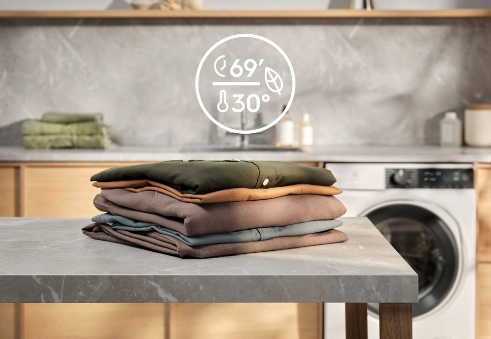 Práčka Electrolux Série 700 EW7F3684SUC biela Hromádka bielizne zemitých farieb na šedom stole. V pozadí linka a práčka Electrolux. Nad kôpkou bielizne symbol programu QuickCare 69 min.