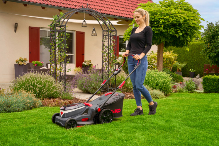Kosačka AL-KO Comfort 38.6 Li 18V (s baterií) Žena kosí trávnik kosačkou AL-KO Comfort na upravenej záhrade pri dome