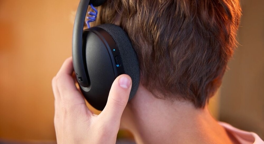 Zadný pohľad na hráča, ktorý pri hraní ovláda náušník herného headsetu Logitech G325 LIGHTSPEED Wireless