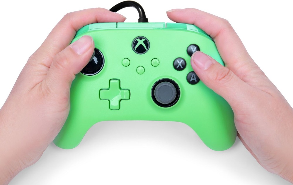 Gamepad PowerA Advantage Plus - Xbox zelený Na obrázku drží človek oboma rukami herný ovládač PowerA Advantage Plus počas hrania. Palce spočívajú na analógových páčkach a tlačidlách, čo ukazuje bežný spôsob ovládania hier. Dobre sú vidieť tlačidlá A, B, X a Y, smerový kríž, funkčné tlačidlá uprostred aj tlačidlo s logom Xbox. Snímka demonštruje ergonomický tvar ovládača, vďaka ktorému pohodlne padne do rúk aj pri dlhšom hraní.