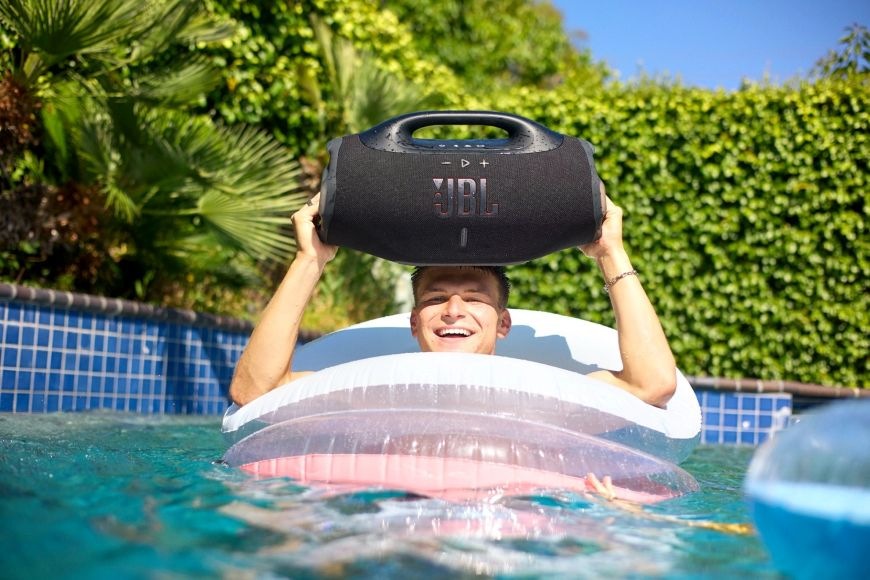 Prenosný reproduktor JBL Boombox 4 čierny Muž drží Prenosný reproduktor JBL Boombox 4 v bazéne