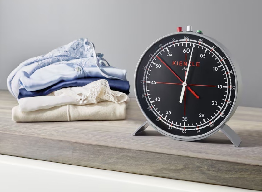 Práčka Electrolux SensiCare 600 EW6T5372C biela Košele zložené na kôpke na stole a vedľa nich budík.