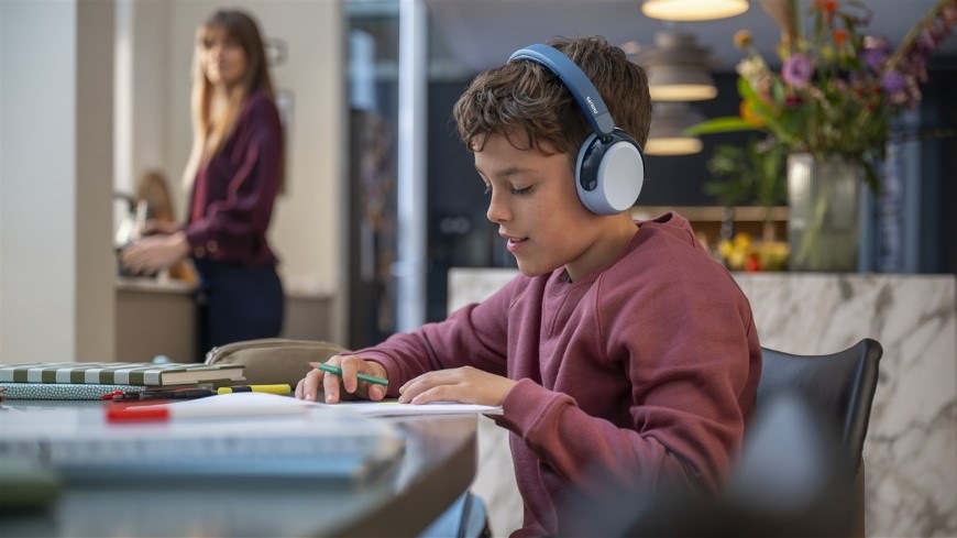 Chlapec pracujúci na domácej úlohe má nasadené slúchadlá Philips TAK5500AL s potlačením hluku
