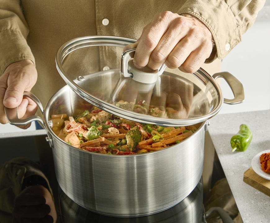 Sada riadu Tefal Extreme E529SA25, 10 ks nerez Muž drží v jednej ruke pokrievku a druhou rukou rukoväť hrnca.