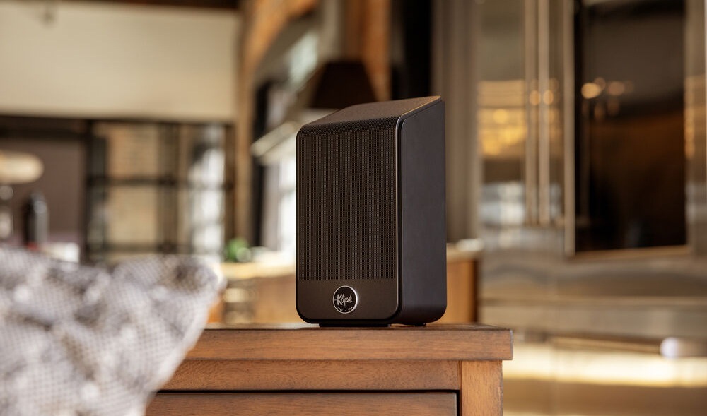 Reproduktory Klipsch Flexus SURR 200 (2 ks) čierne Jeden reproduktor Klipsch Flexus SURR 200 stojí na stole, na pozadí je rozostrená miestnosť