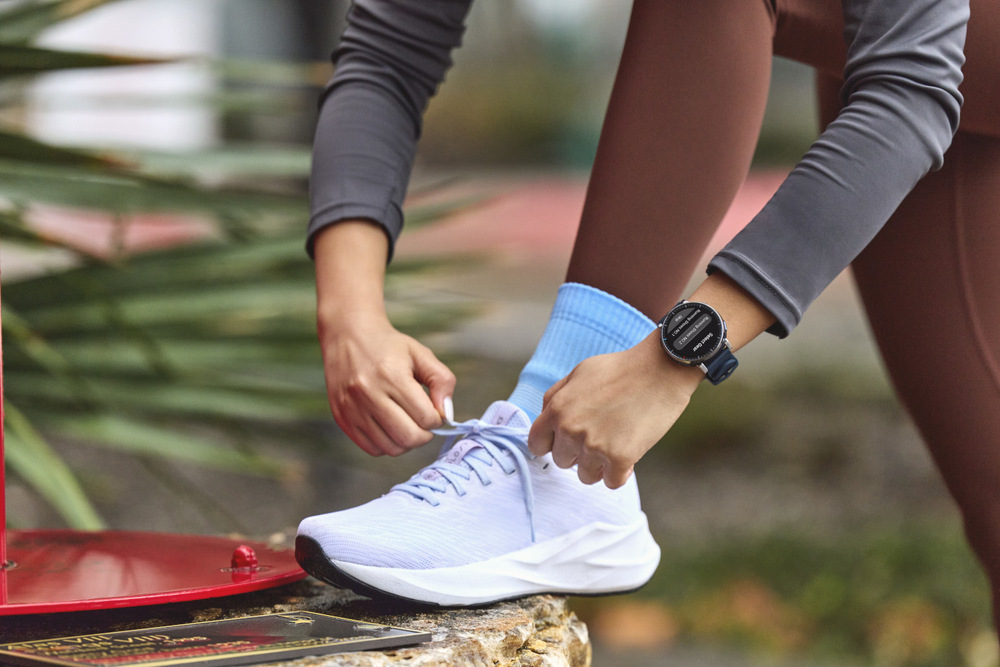 Žena si zaväzuje bežeckú topánku a na zápästí má hodinky Amazfit Active 3 Premium