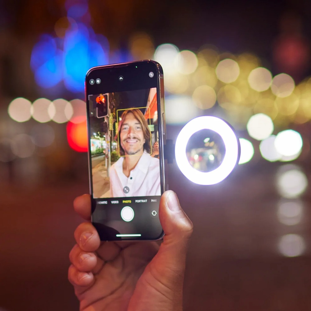 Svetlo ShiftCam SnapPocket Light čierne Ruka drží smartfón so svetlom SnapPocket av pozadí je tma