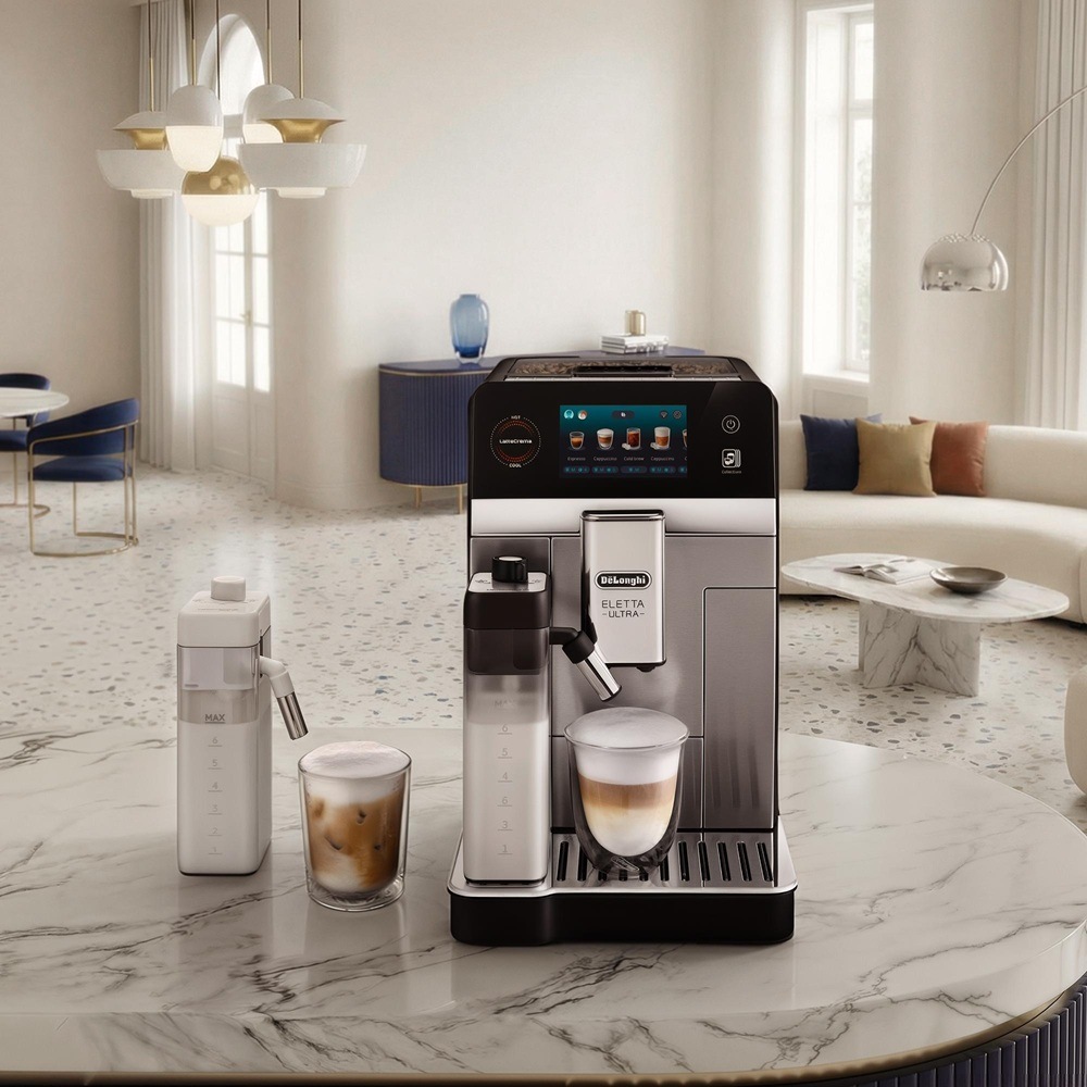 Automatický kávovar De'Longhi Eletta Ultra ECAM 470.85.MB čierne/nerez V svetlej modernej obývačke stojí na mramorovom stole automatický kávovar De’Longhi vedľa pohárov s penovým horúcim a ľadovým kávovým nápojom.