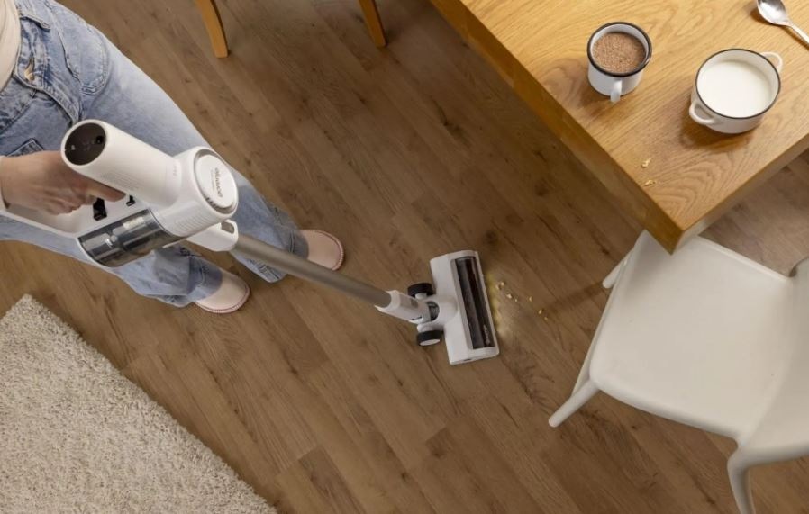človek vysáva omrvinky vysávačom Gorenje SVC216290FFW s osvetlenou hubicou, vysáva okolo stola.