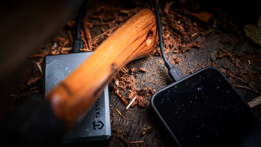 Smartphone položený v prírode napojený na powerbanku cez kábel Tactical Stitch Thread