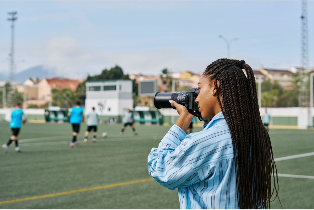 Fotografka zhotovuje snímky futbalového zápasu fotoaparátom Sony RX10 V s výkonným teleobjektívom