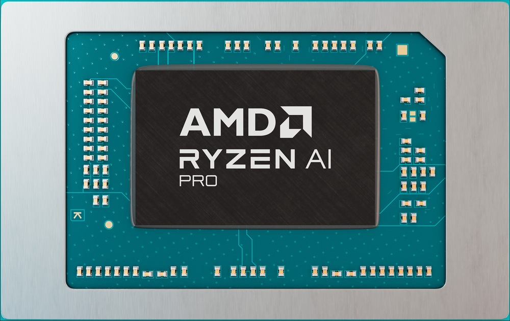 Detailný záber procesora AMD Ryzen AI Pro na modrozelenej doske plošných spojov. Čip má strieborné písmo a je obklopený niekoľkými zlatými tranzistormi.
