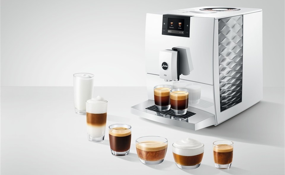 Automatický kávovar Jura C9 Piano White biely Automatický kávovar Jura C9 Piano White chystá dva poháre kávy, pred kávovarom stojí šesť pohárov s rôznymi druhmi kávy
