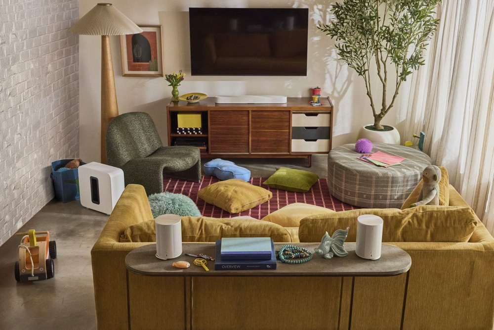 Biely soundbar Sonos Beam Ultra, subwoofer a dva reproduktory rozmiestnené v útulnej rodinnej obývačke s TV.