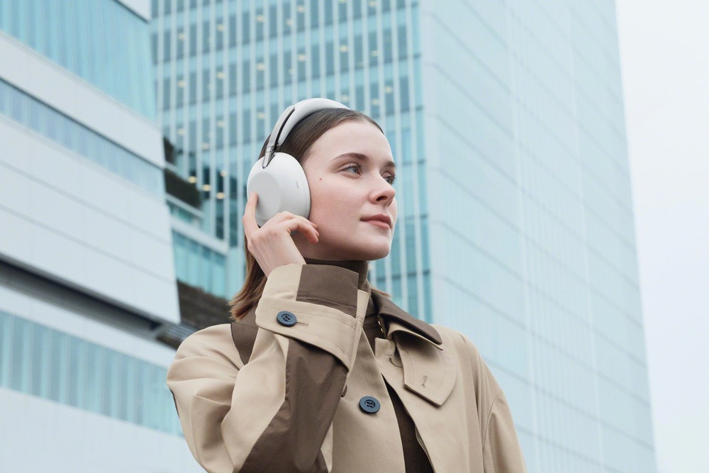 Slúchadlá Sony WH-1000X THE COLLEXION - Bezplatná predĺžená záruka po registrácii čierna farba Žena dotýkajúca sa náušníka slúchadiel Sony WH-1000X THE COLLEXION