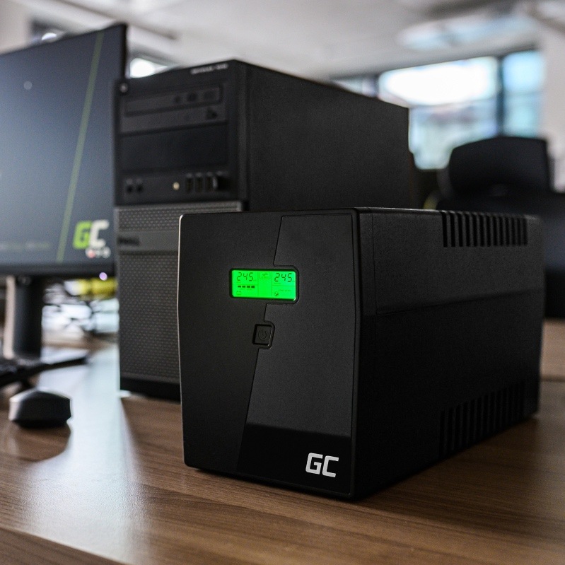 Záložný zdroj Green Cell Microsine 2000VA LCD čierny Na obrázku je záložný zdroj Green Cell Microsine položený na drevenom pracovnom stole vedľa stolného počítača a monitora. Má čierne hranaté telo, na čelnej strane zeleno podsvietený displej s prevádzkovými údajmi, pod ním tlačidlo zapnutia a dole logo GC. V pozadí je počítačová skriňa a monitor, takže fotka ukazuje použitie zdroja v bežnom pracovnom prostredí. Zariadenie pôsobí robustne, prakticky a je určené na ochranu počítača pri výpadku prúdu.