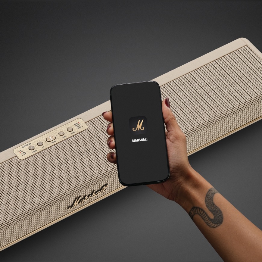 Ruka drží smartfón s mobilnou aplikáciou kompatibilnou so soundbarom Marshall Heston 60″ width=