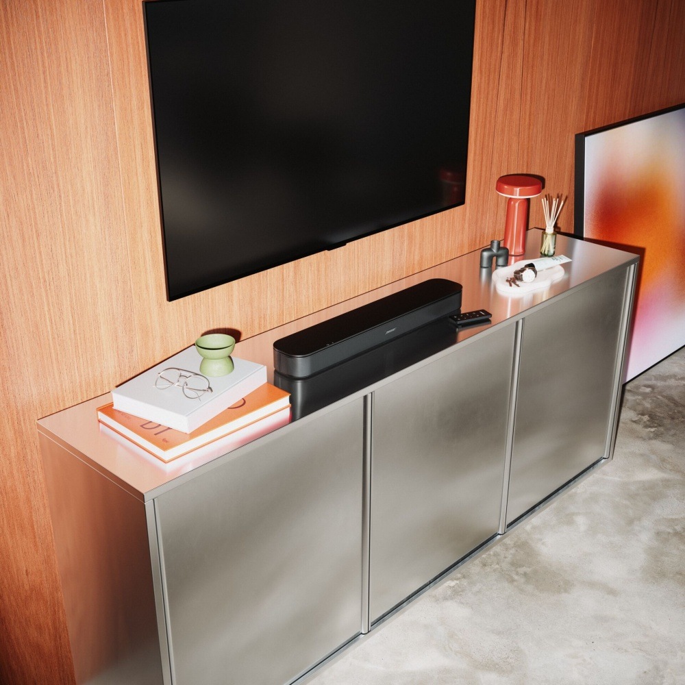 Soundbar Bose TV Speaker 2nd.Gen. čierny Soundbar Bose TV Speaker na komode pod televíziou v štýlovej miestnosti s dreveným obkladom.