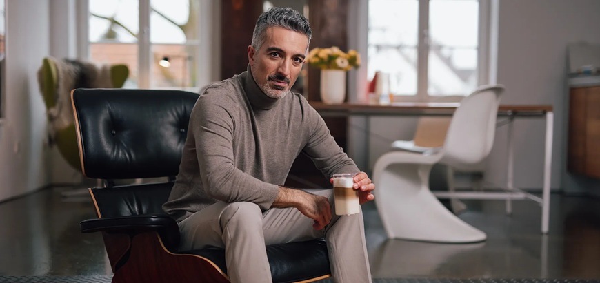 Muž sediaci v kresle a pijúce caffé latté.