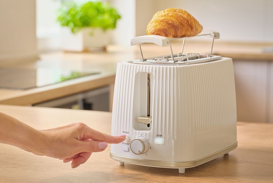 Hriankovač Sencor STS 7510WH biely Žena nastavuje na hriankovači funkciu ohrevu. V pozadí je moderná kuchyňa.