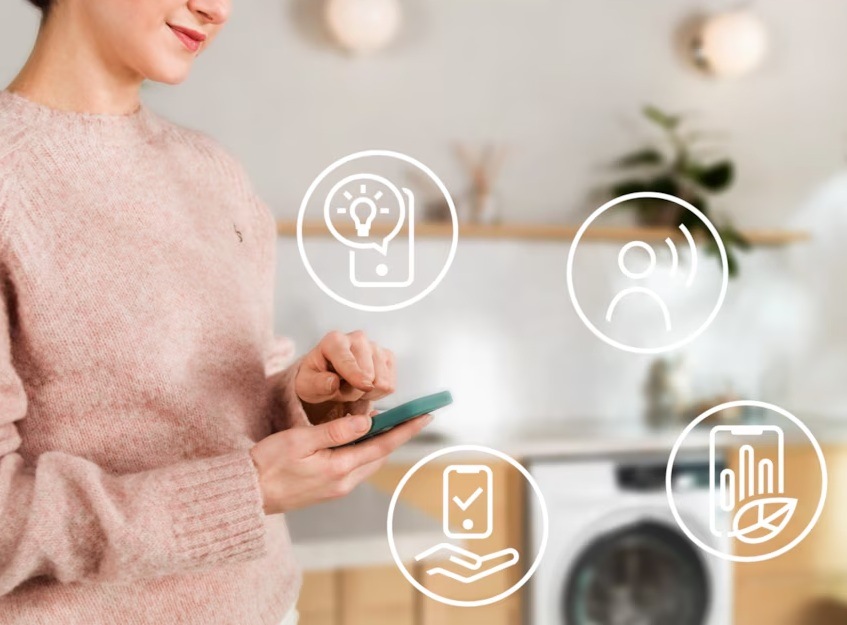 Sušička bielizne Electrolux PerfectCare 900 EW9D595CC biela Žena ovláda sušičku Electrolux cez mobilnú aplikáciu. Okolo sú symboly pre jednotlivé funkcie.