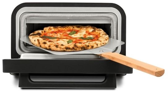 Pizza rúra s otvorenými dvierkami a pizza lopatou, na ktorej leží čerstvo upečená pizza s chrumkavým okrajom.