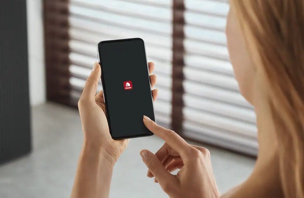 Žena drží v ruke mobilný telefón, na displeji je aplikácia Miele