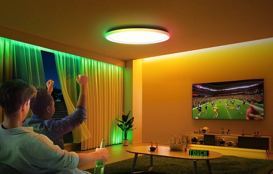LED stropné svietidlo Yeelight Inteligentné s osvetlením po okraji Mars C300 biele Detail obrázku muža s dieťaťom sediaci v obývacej izbe a sledujúci športový zápas s farebným osvetlením izby.