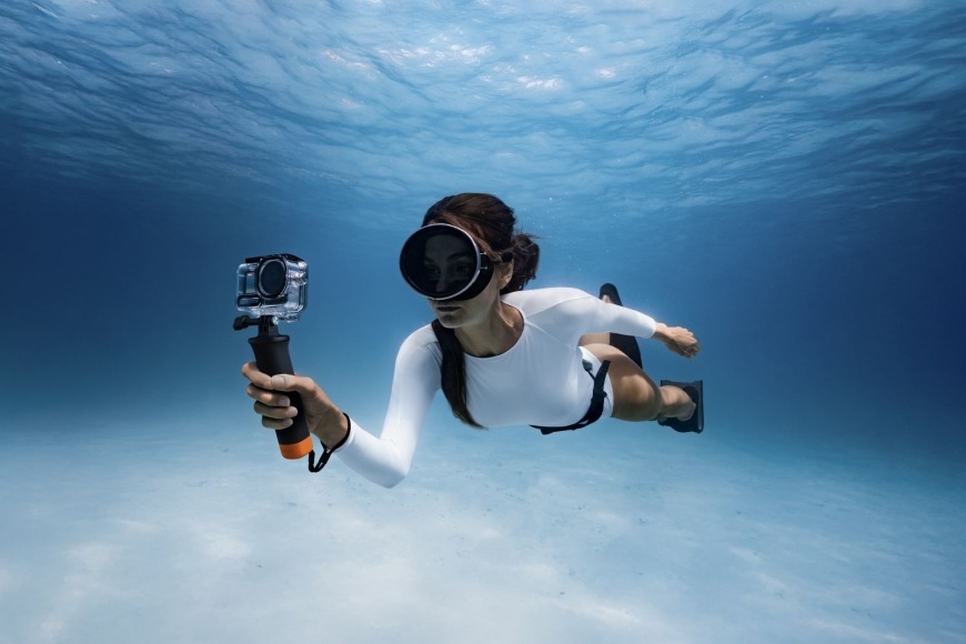 Sada príslušenstva DJI Osmo Action 6 Diving Accessory Kit čierna Žena plávajúca pod morskou hladinou má akčnú kameru vybavenú príslušenstvom na potápanie DJI Diving Accessory Kit