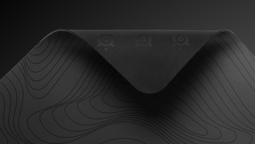 Podložka pod myš SteelSeries QcK Large, Topographic čierna Odklopený roh podložky QcK Topographic odhaľujúci gumovú spodnú stranu